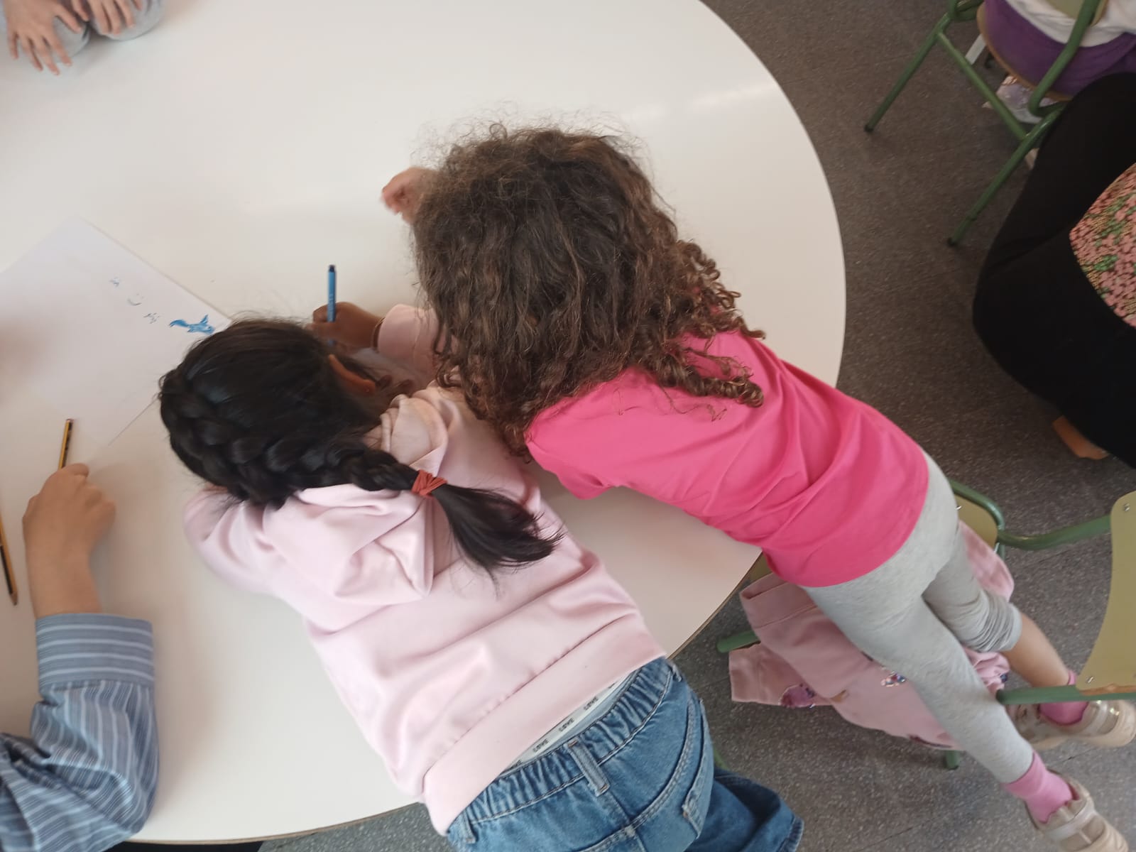 Dues nenes dibuixant juntes en una activitat de cooperació i cura a l'aula