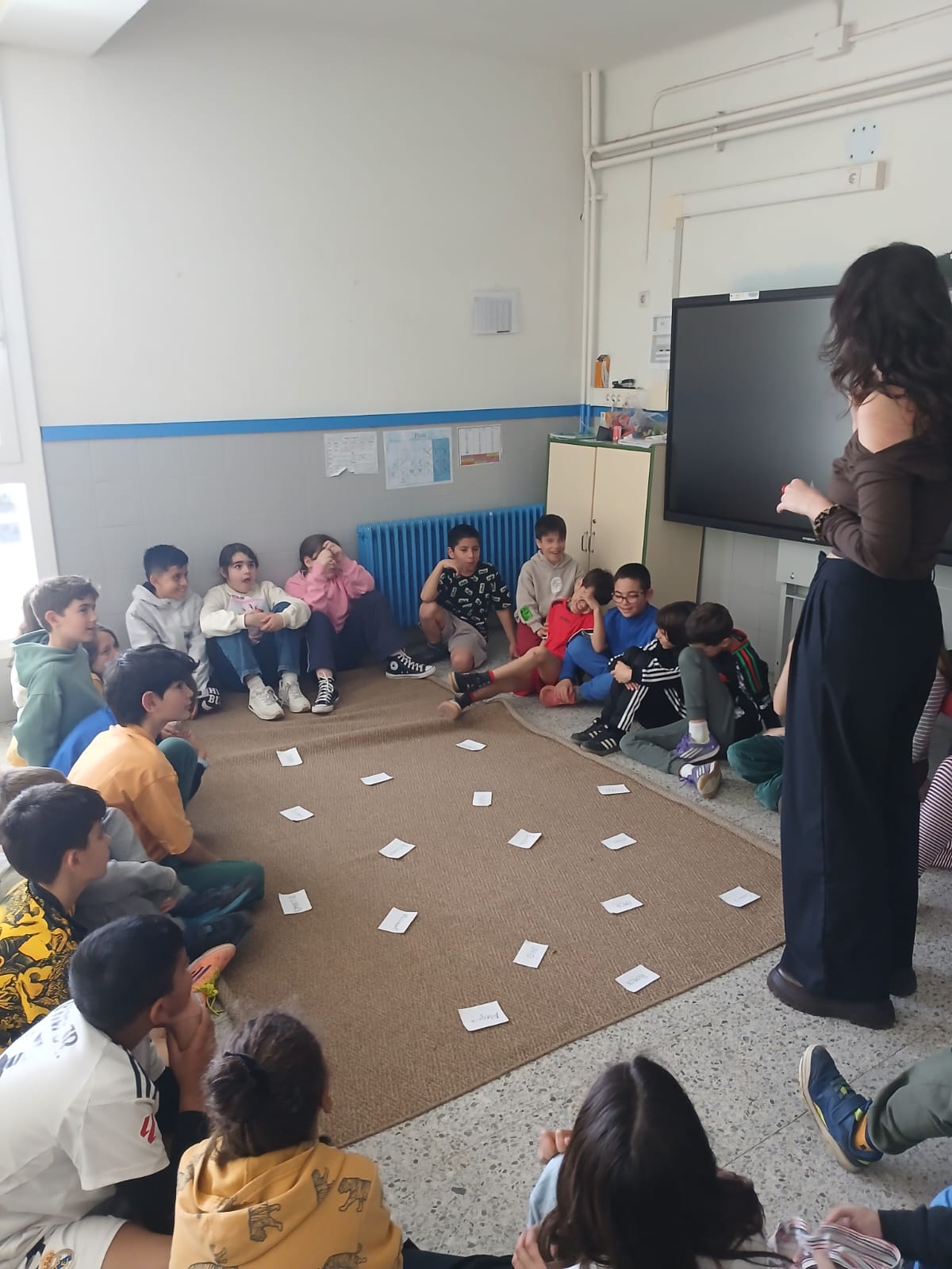 Infants asseguts en cercle escoltant la mediadora durant una dinàmica de convivència a l'aula