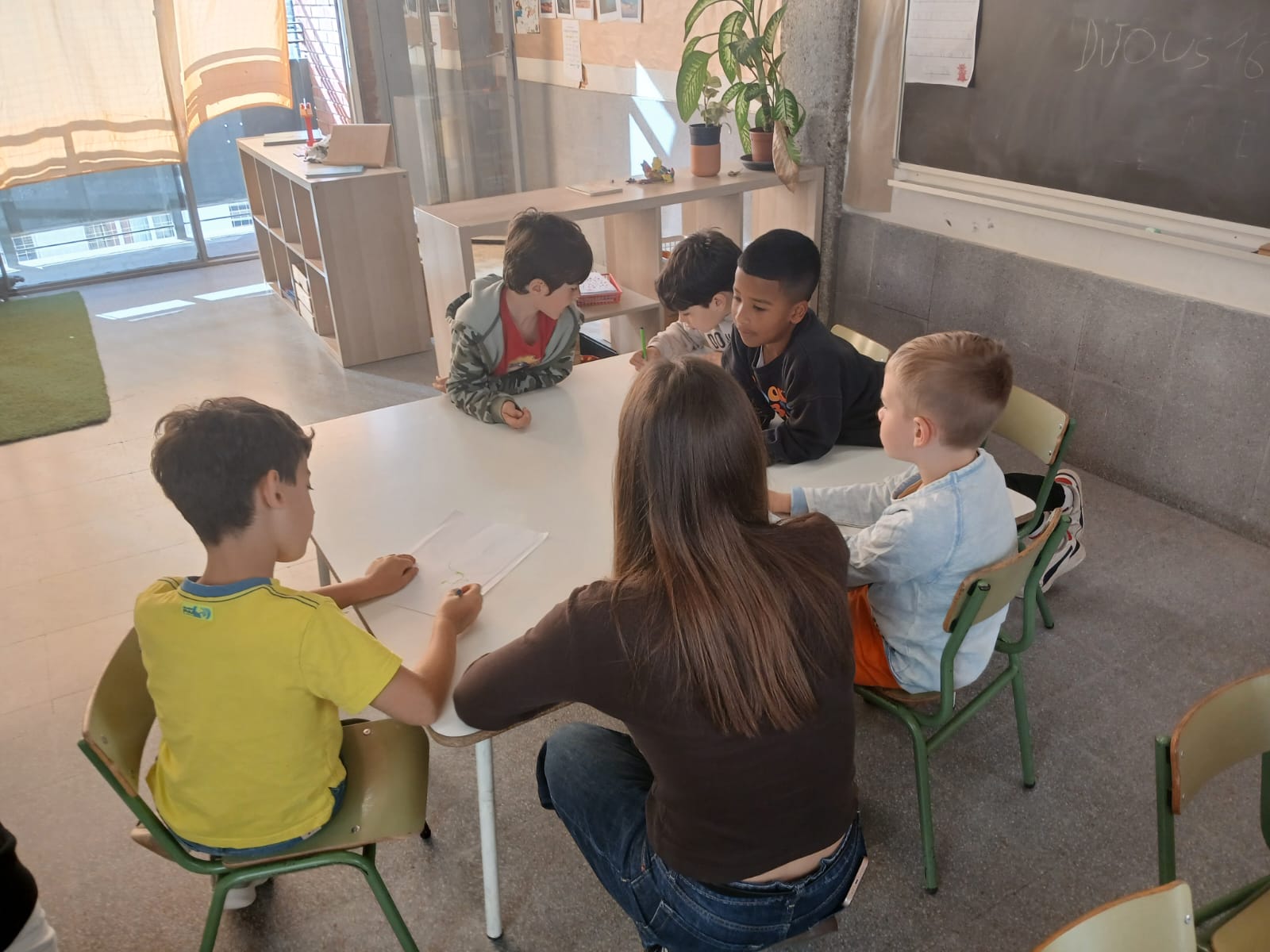 Petit grup d'infants amb la mediadora dialogant al voltant d'una taula rodona