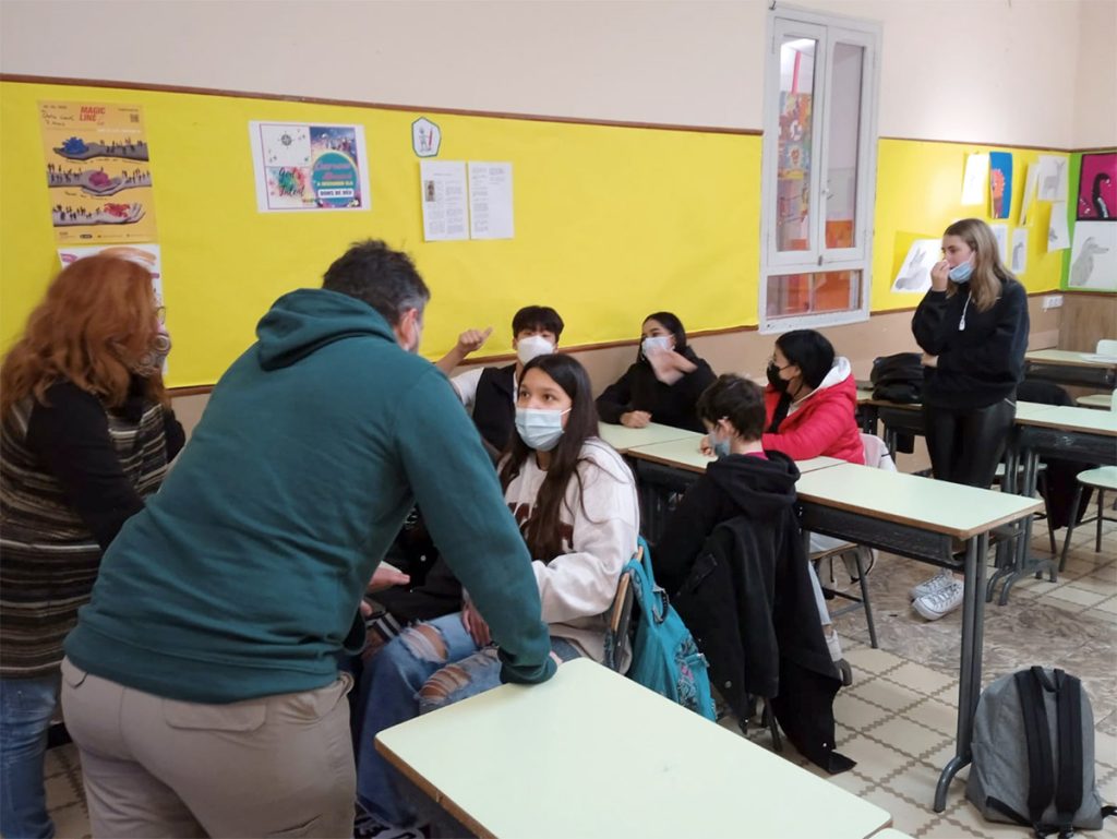 Facilitador acompanyant un grup d'adolescents en una sessió de mediació i resolució de conflictes a l'aula