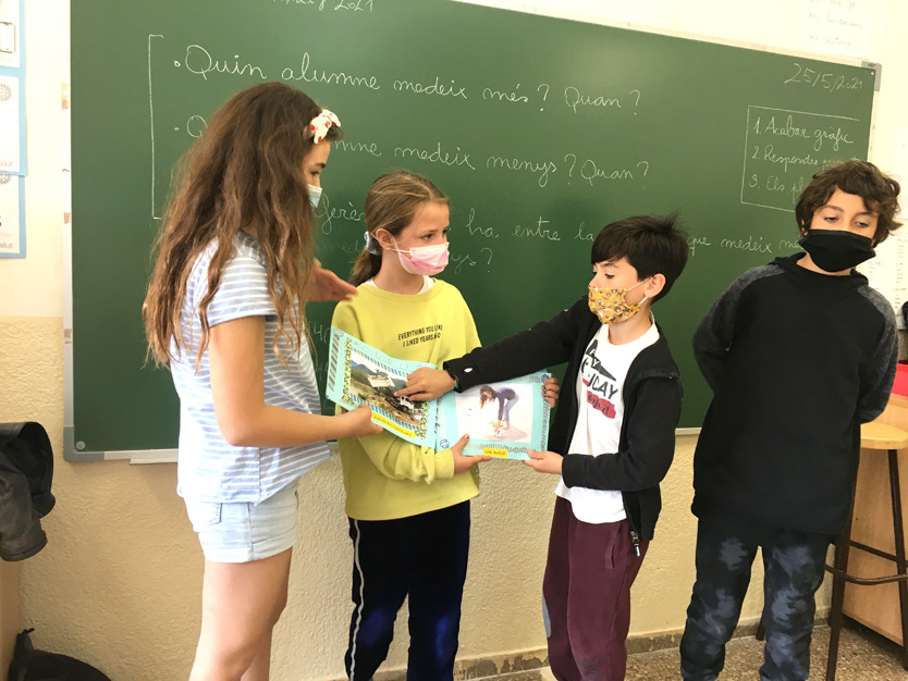 Alumnes de primària presentant un àlbum il·lustrat creat dins el projecte d'Aprenentatge Servei sobre gestió de conflictes i art a l'aula