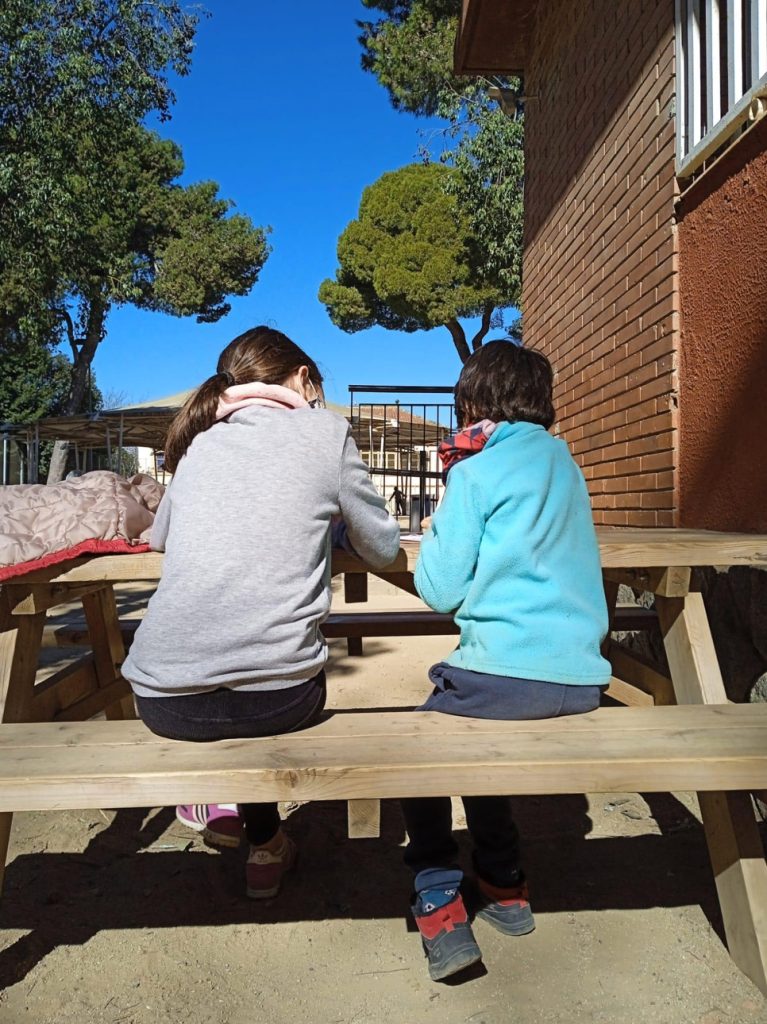 Dues alumnes treballant juntes a una taula del pati en una sessió de mentoria del projecte Ens ajudem a créixer