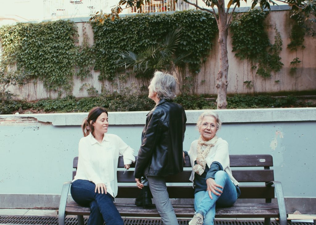 Joves i persones grans dialogant en un banc en un espai comunitari de Barcelona
